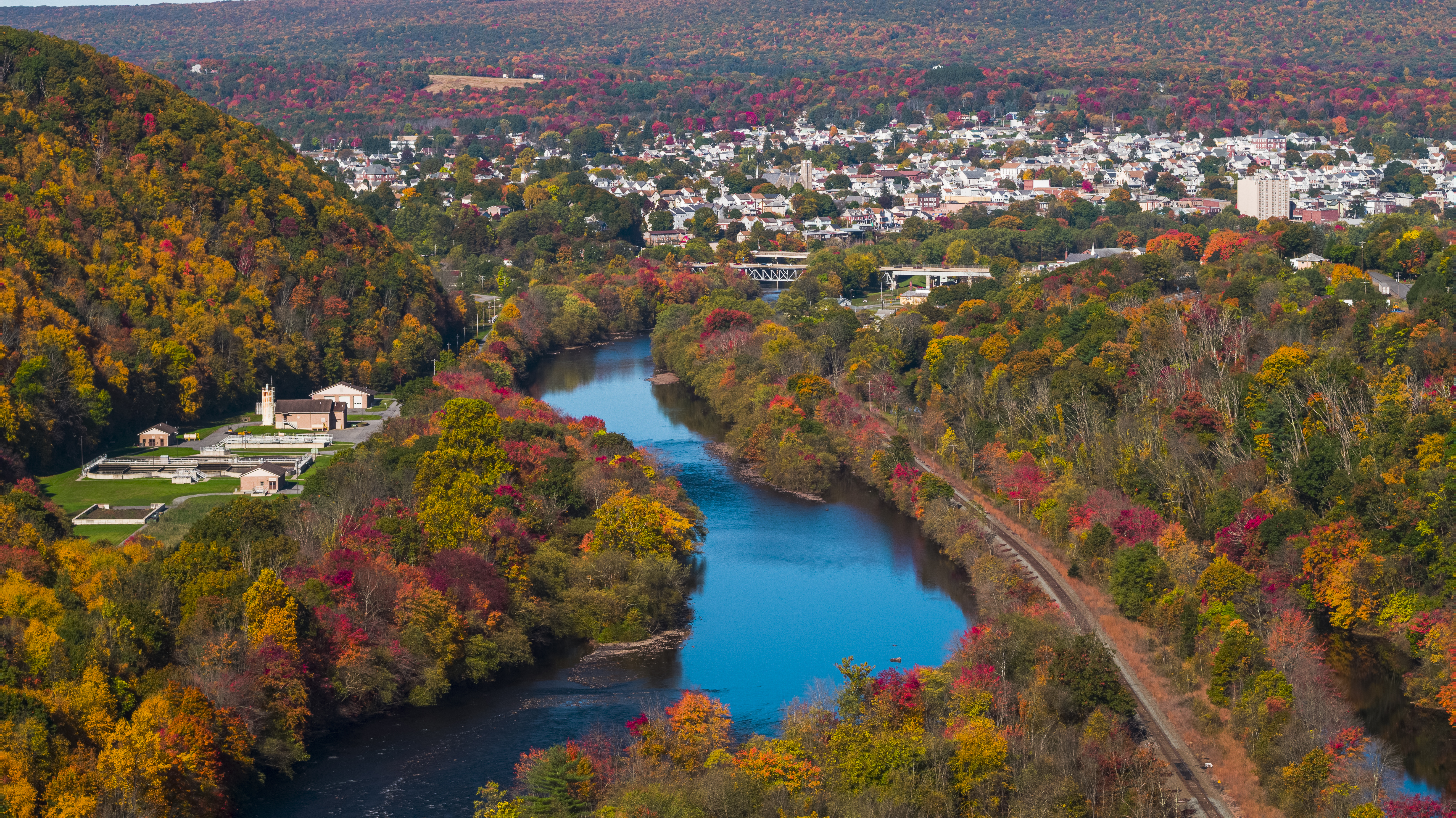 An aerial view of a small town located near a river in the fall 